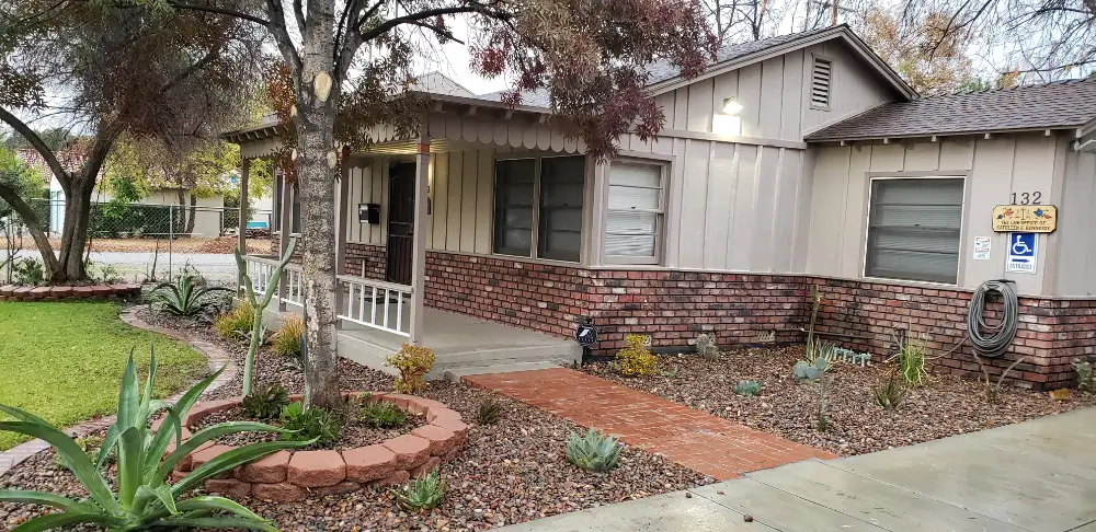 Exterior of Redwood Counseling’s Hemet office, with a brick walkway, trees, and landscaped grounds.