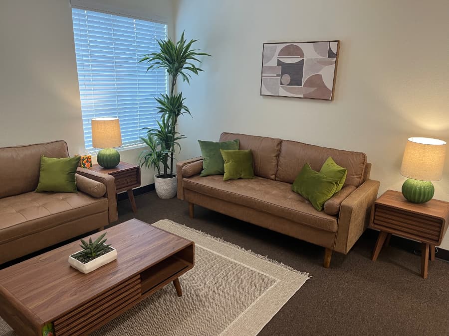 Mental health counseling room at Redwood Counseling’s Temecula office, with comfortable sofas, green cushions, and warm lighting.